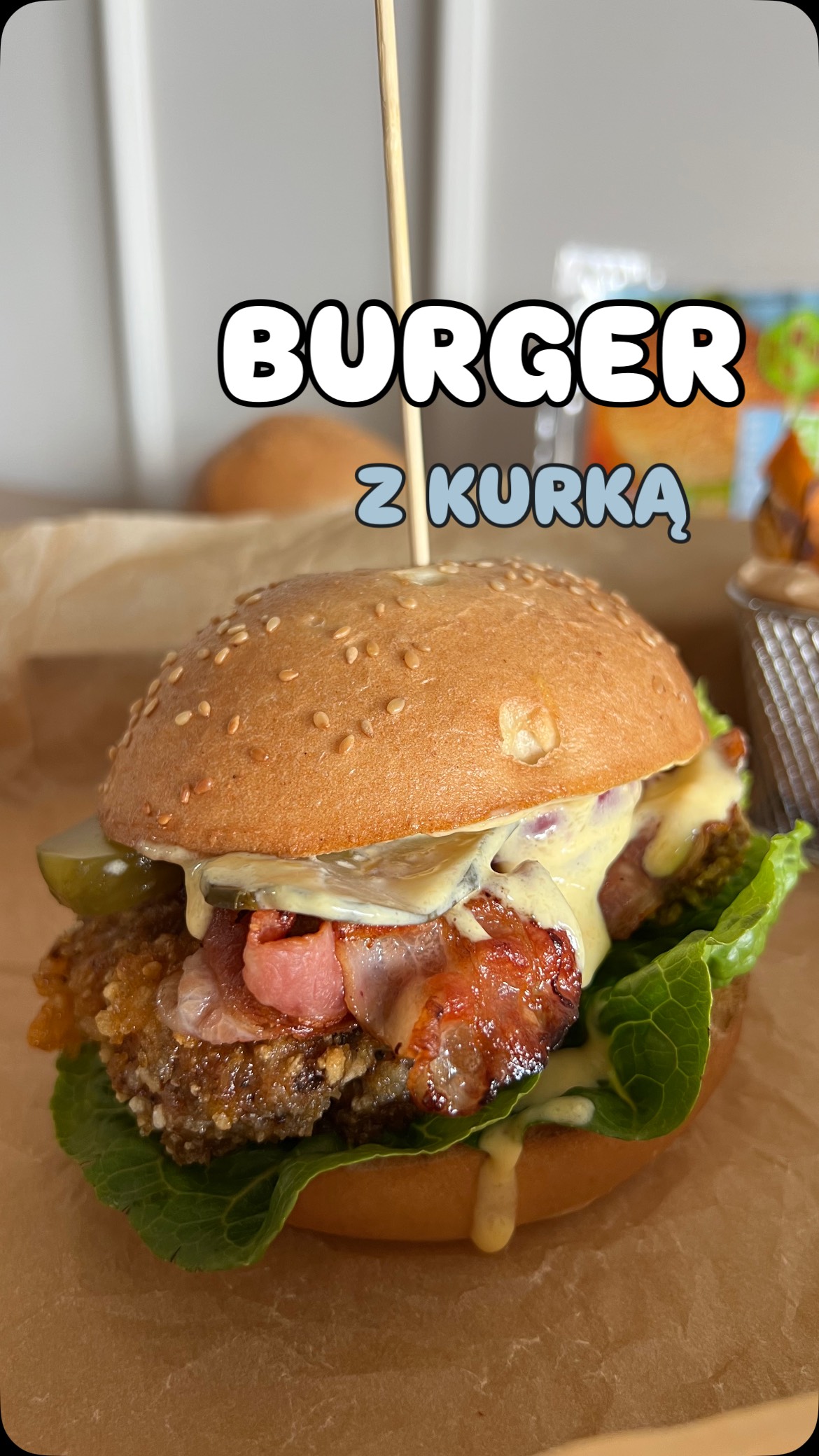 Burger z kurką z bezglutenową bułką, bekonem, sałatą, kisoznym ogórkiem, czerwoną cebulą i sosem mango-mayo